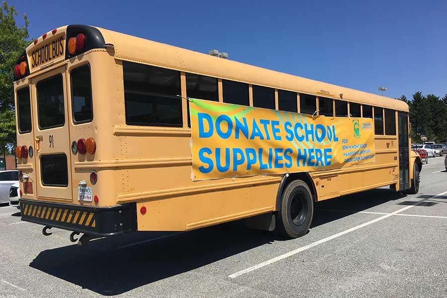 Photo of a school bus with a banner that says "Donate School Supplies Here."